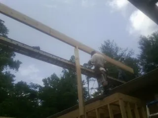 Carpenter setting a ridge beam over a new addition frame — Ice Dam Removal by Roofing Brothers in Shacklefords