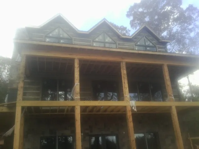 Dormers and porch framing on a large log home under construction — Roof Coating work by our crew in Shacklefords