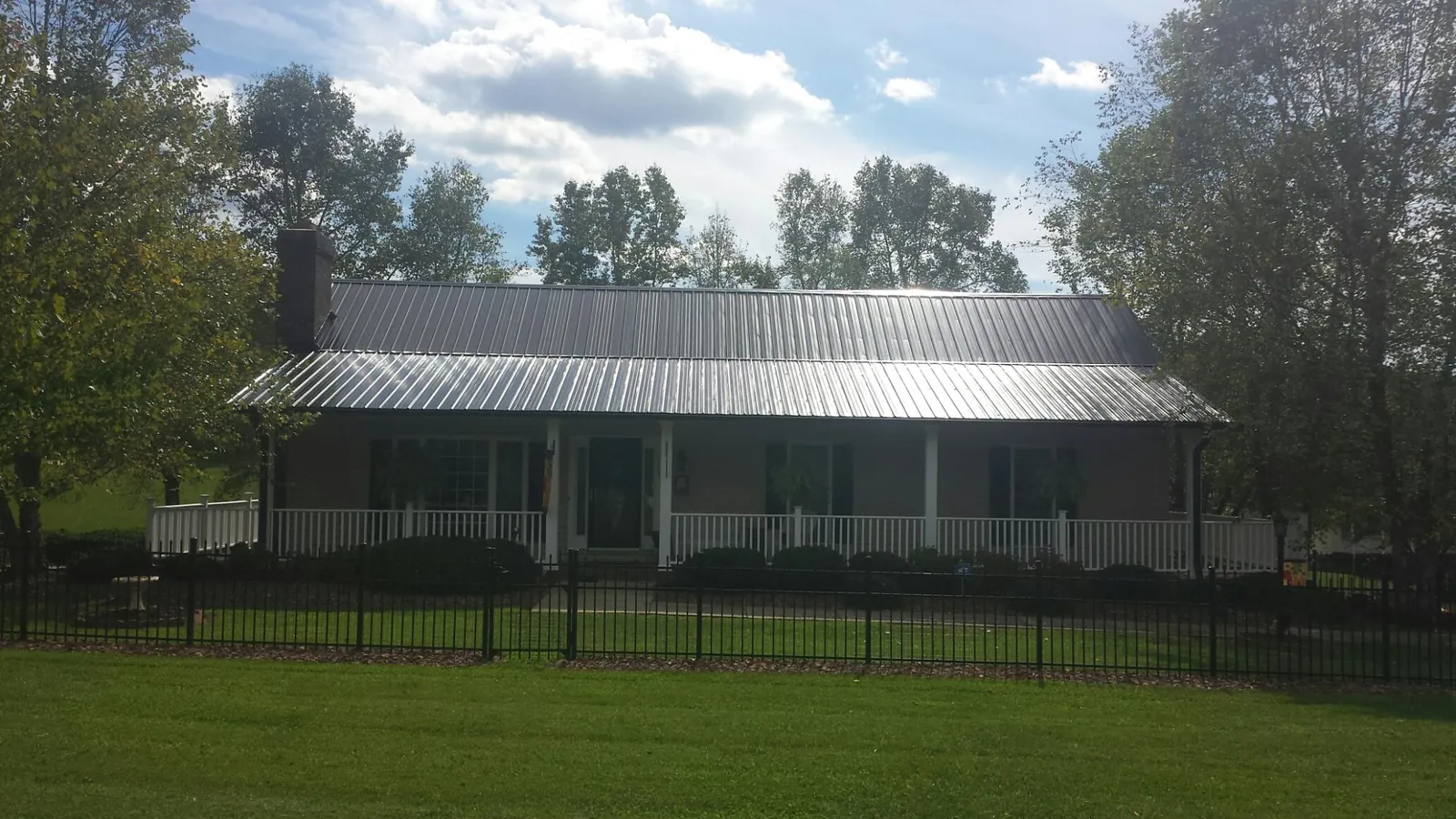 Gray metal roof on a brick ranch with a full width front porch — Gutter Guard Installation work by our crew in Shacklefords