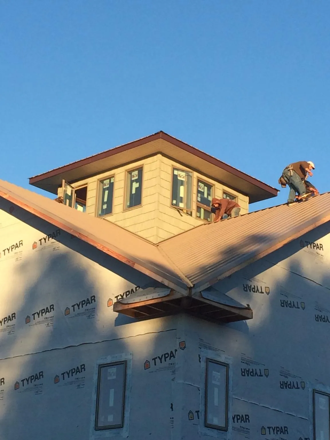 Roofers working around a rooftop cupola on a new metal roof at sunset — Roof Waterproofing in Shacklefords by Roofing Brothers